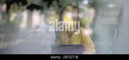 View through glass window of two businesspeople sitting in glass partition and working together Stock Photo