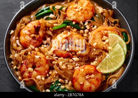 Prawn Pad See Ew in black bowl at dark slate background. Pad See Ew is thai cuisine dish with rice noodles, prawns, soy and oyster sauces and greens. Stock Photo
