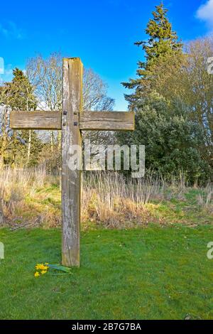 Wooden Christian cross in grounds of Balmerino Abbey, Fife, Scotland, UK on a sunny spring day with blue sky and clouds Stock Photo