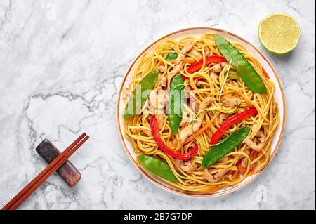 Chicken Lo Mein on white marble background. Lo Mein is Chinese cuisine dish with chicken meat, egg noodles, vegetables and sauces. Chinese Food. Stir Stock Photo