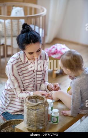 Young mother applying plaster on daughter's knee Stock Photo