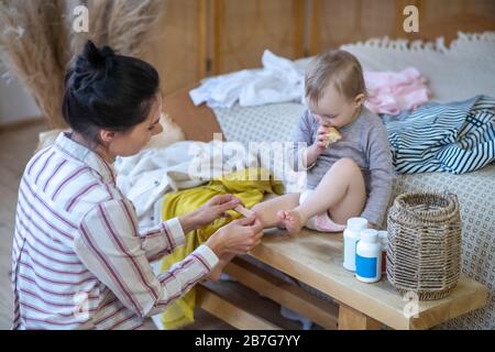 Young mother applying plaster on daughter's knee Stock Photo