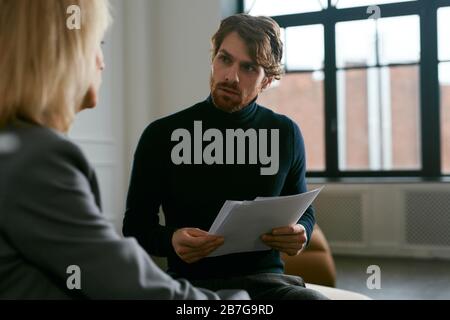 Waist up portrait of handsome bearded man talking to female partner while discussing work in office interior, copy space Stock Photo