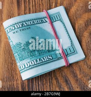 A pack of dollars tied with an elastic band lies on wooden boards Stock Photo