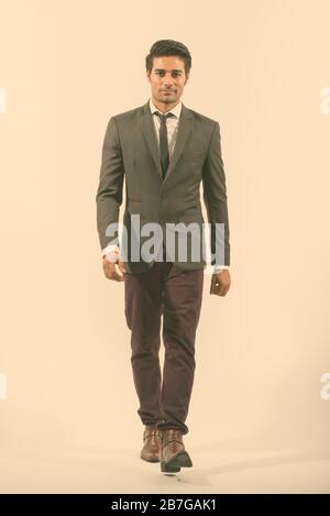 Full body shot of young handsome Persian businessman walking Stock Photo