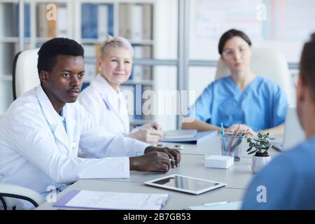 Portrait of young African-American doctor listening to colleague committee during medical conference, copy space Stock Photo