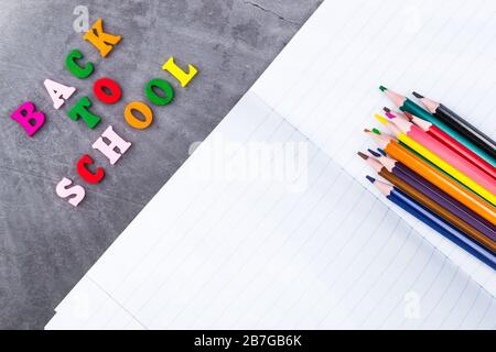 The layout of school supplies on a dark gray background. Top view, the sun's rays from the side. Back to school. Flat lay Stock Photo