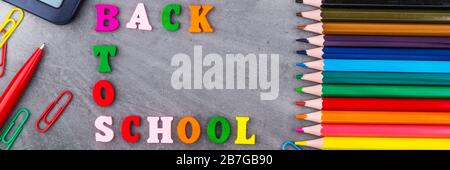 The layout of school supplies on a dark gray background. Top view, the sun's rays from the side. Back to school. Flat lay Stock Photo