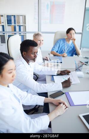 High angle view at young African-American doctor sitting at table during medical conference with colleagues, copy space Stock Photo