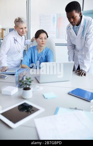 Multi-ethnic group of doctors using computer while working on medical project together, copy space Stock Photo