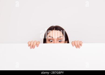 Young smiling surprised girl appear near big poster and looking down with big eyes at place for copy space Stock Photo