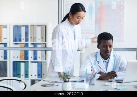 Portrait of two ethnic young doctors using laptop in med school or internship, copy space Stock Photo