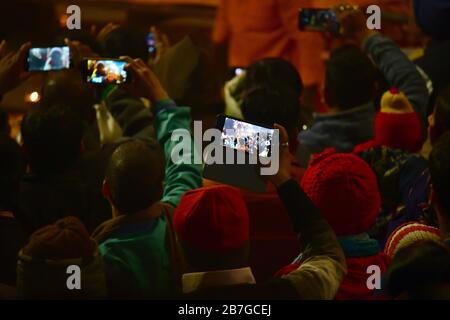Hundreds of people gathering at the evening Aarti ceremony.  People filming the ceremony with smartphones.  Varanasi, India Stock Photo