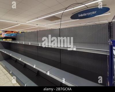 empty shelf for toilet paper in a supermarket in germany. due to the corona virus pandemic many german hamster purchases. Stock Photo
