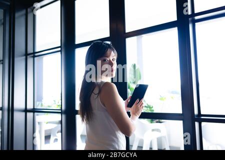 Asian woman using digital tablet and looking at the camera Stock Photo
