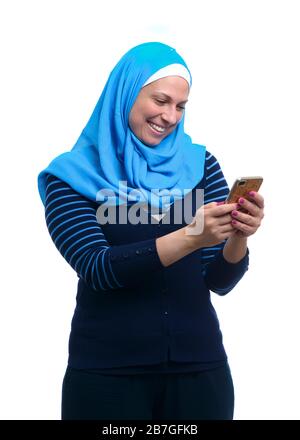 Portrait of arab cheerful cute beautiful woman chatting by mobile phone isolated over white wall background, happy message notification. Stock Photo