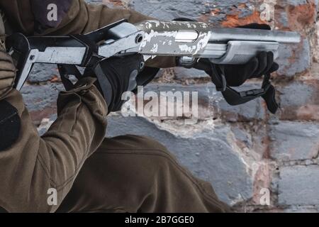 A military man with a shotgun aims at the target. Close up. Stock Photo