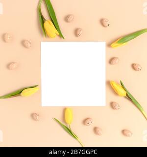 Top view of easter eggs and flowers on a beige background. Holiday concept with place for text. Stock Photo