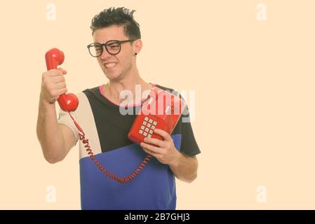 Angry young man holding old telephone Stock Photo