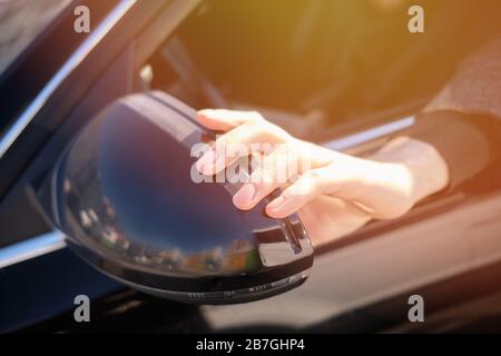 Hand adjusts the side view mirror of car. Close up. Stock Photo