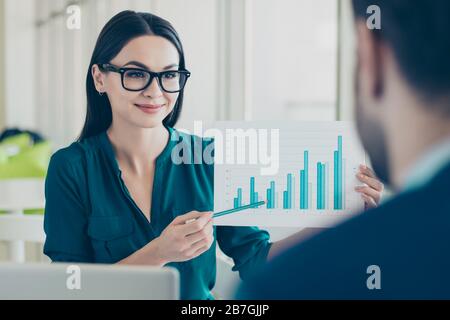 Smart young woman in glasses showing graph to her business partner Stock Photo
