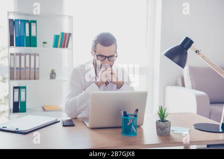 Stylish concentrated businessman in white shirt works in office with documents while sitting at the table Stock Photo