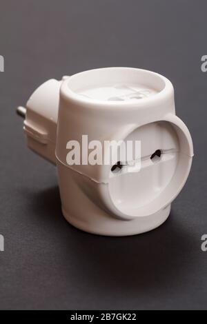 Close-up white plastic electrical tee connector with three sockets on a black background. Stock Photo