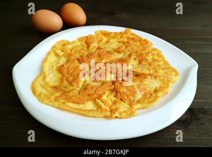 Plate of Thai Style Omelette on the Dark Brown Wooden Table Stock Photo