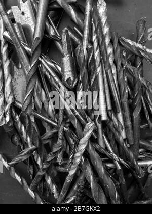 Used drill bits in a pile. A cutting tool for making holes in materials with power or hand drills. A collection found in a garage during a DIY session Stock Photo