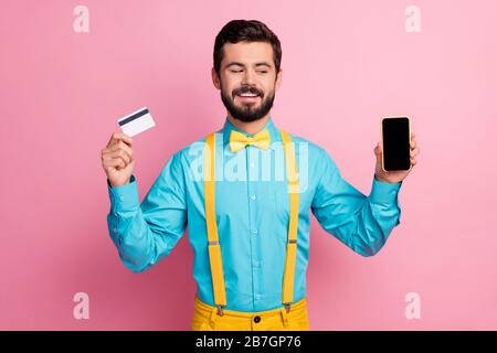 Portrait of his he nice attractive cheerful cheery confident bearded guy wearing mint blue shirt holding in hands cell bank card online pay app Stock Photo