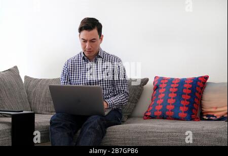 Man working from home with a laptop in the living room Stock Photo