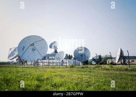 Barbed wire fence around satellite links center with telecommunication tower equipped with radar antennas, cybercrime and cybersecurity concept Stock Photo