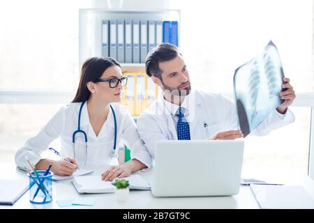 Two serious confident doctors checking the x-ray of their patient and making a diagnosis Stock Photo
