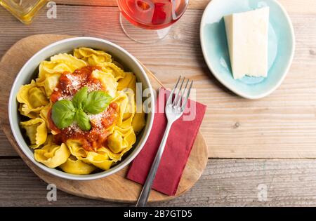 Homemade dinner tortellini with tomato sauce arrabbiata and cheese with a glass of wine on the side. Top view. Stock Photo