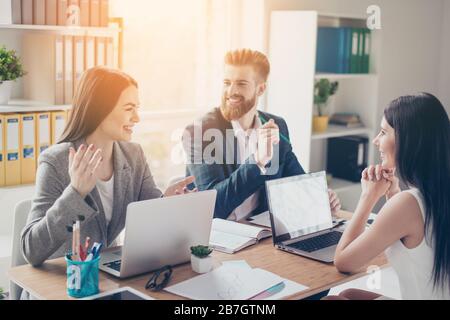 A group of cheerful successful young people discussing business ideas for their company in sunny workspace in formal wear Stock Photo