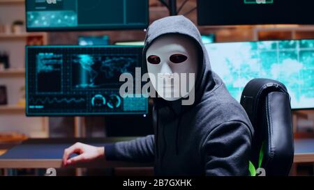 Wanted cyber criminal wearing a white mask while looking at camera. Stock Photo