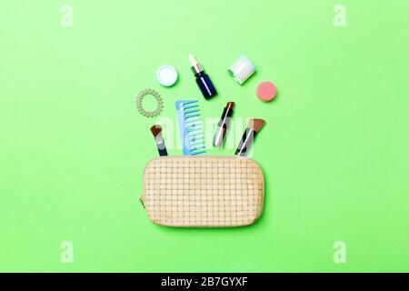 Top view od cosmetics bag with spilled out make up products on green background. Beauty concept with empty space for your design. Stock Photo
