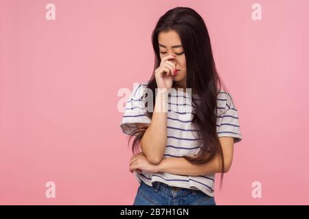 Portrait of upset girl with long brunette hair in striped t-shirt crying and hiding gloomy face in hand, feeling lonely frustrated, depressed emotions Stock Photo