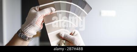 Repairmans hands with color palette over grey renovated walls Stock Photo