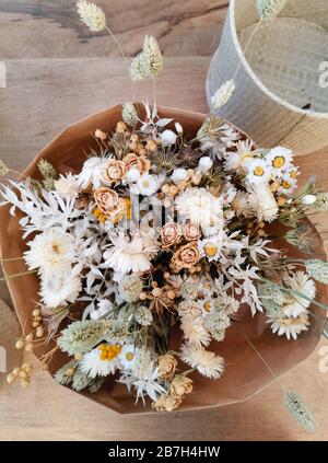 Dried flower arrangement for a wedding in neutral soft beige and white tones on a wooden background Stock Photo