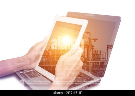 Double exposure one using tablet and laptop computer and construction site representing modern engineering, construction and property industry and tec Stock Photo