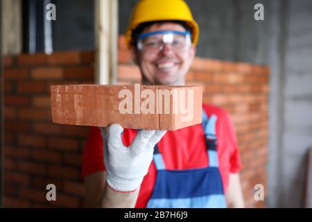 Smiling male builder showing fine quality brick material in camera Stock Photo