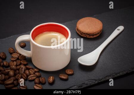 Cup of coffee, coffee beans, macaroons and spoon on black background. Top view. Stock Photo