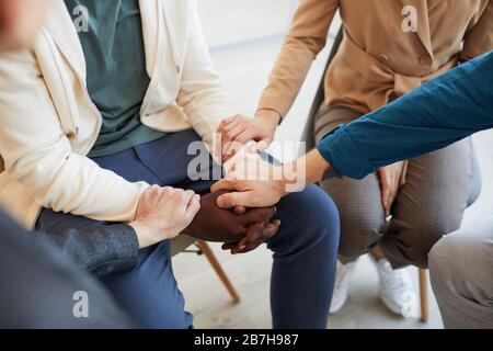 High angle closeup of people holding hands while comforting each other in psychology support group, copy space Stock Photo