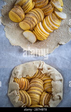 Raw apple galette - pie on white baking parchment. Copy space, flat lay. Stock Photo