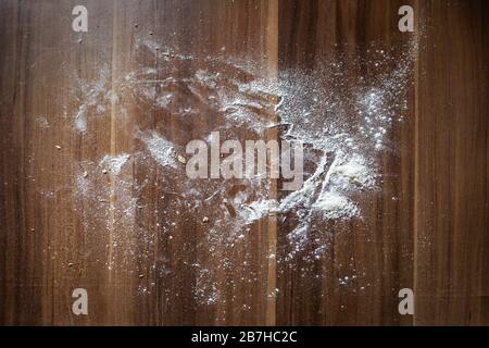 Flour is scattered on a brown wooden table background. View from above Stock Photo