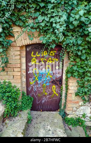 Small purple door with graffiti and ivy in he small town of Collbato on the slopes of Montserrat, Barcelona, Spain Stock Photo
