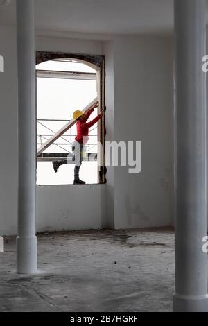 Worker balancing on a window while working. Building site Stock Photo