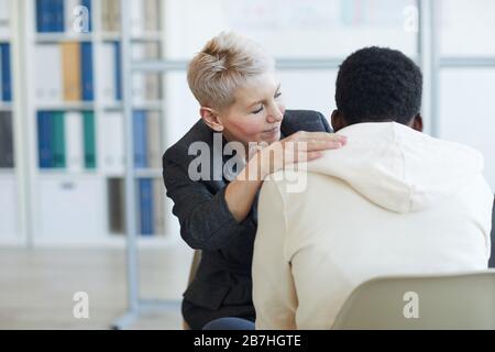 Portrait of mature female psychologist helping young patient in therapy session, copy space Stock Photo