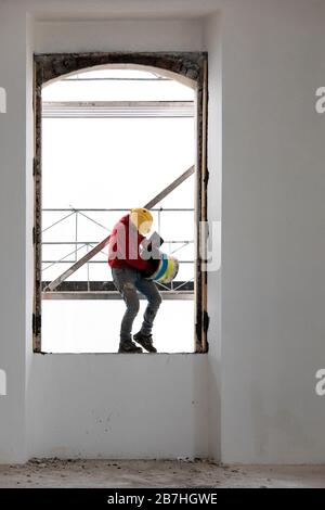 Worker balancing on a window while working. Building site Stock Photo